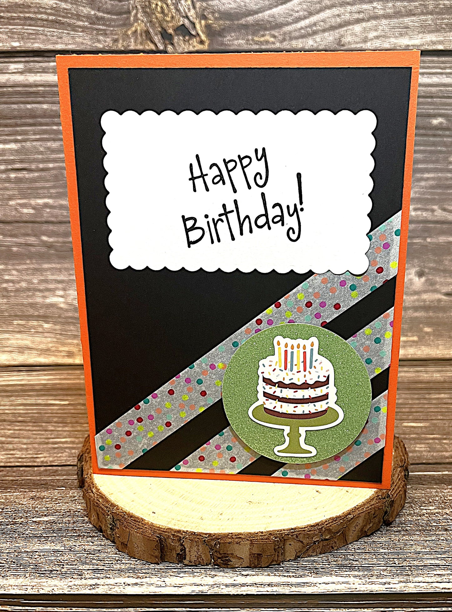 Birthday card 4 1/4 x 5 1/2 inches with orange base, black accent paper, polka dot stripes, and cake on green glitter circle