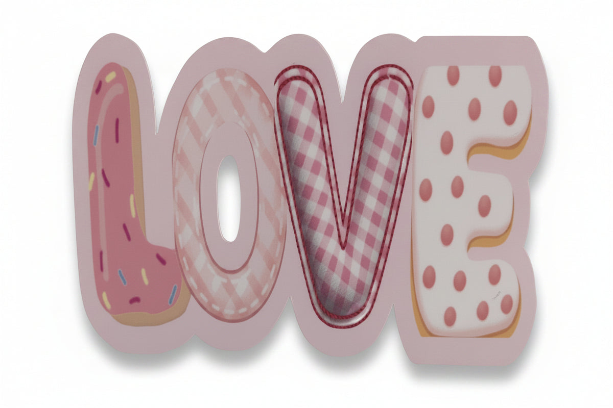 A vinyl sticker spelling LOVE in rounded letters, styled like donuts or pastries with pink and white patterns, shown on a tabletop.