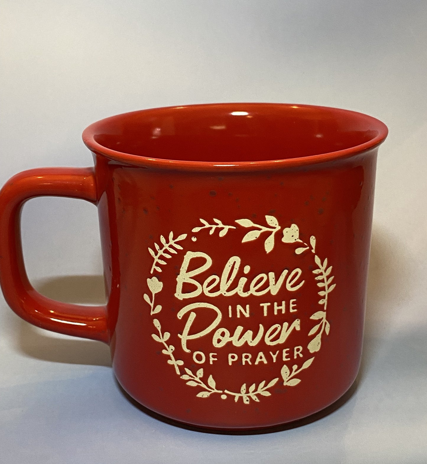 Red mug with 'Believe in the Power of Prayer' text on a white background