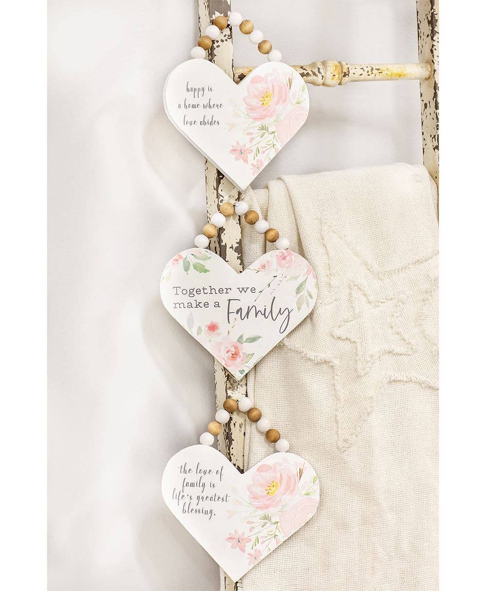 White heart-shaped wooden signs with pink flowers, jute hangers with beads, each with a unique family-themed quote.