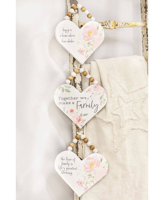 White heart-shaped wooden signs with pink flowers, jute hangers with beads, each with a unique family-themed quote.