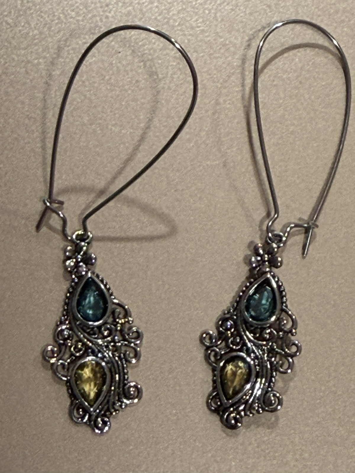 Stella baroque-style silver-toned dangle earrings with blue and green teardrop stones, featuring long interchangeable kidney wires and measuring approximately 2 1/2 inches long.