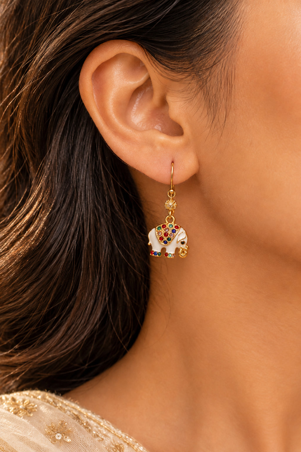 A pair of gold-tone dangle earrings with white elephant charms decorated with multicolored rhinestones.