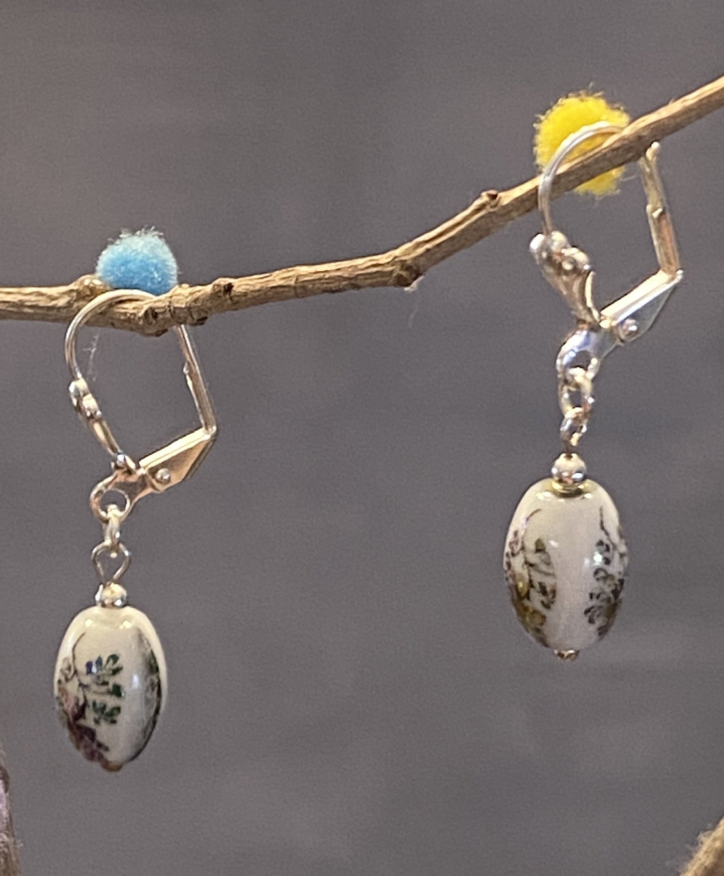 Hazel earrings feature white glass beads with a delicate flower design. Silver-toned base metal, lever backs, approx. 1½" long. Elegant and timeless charm.