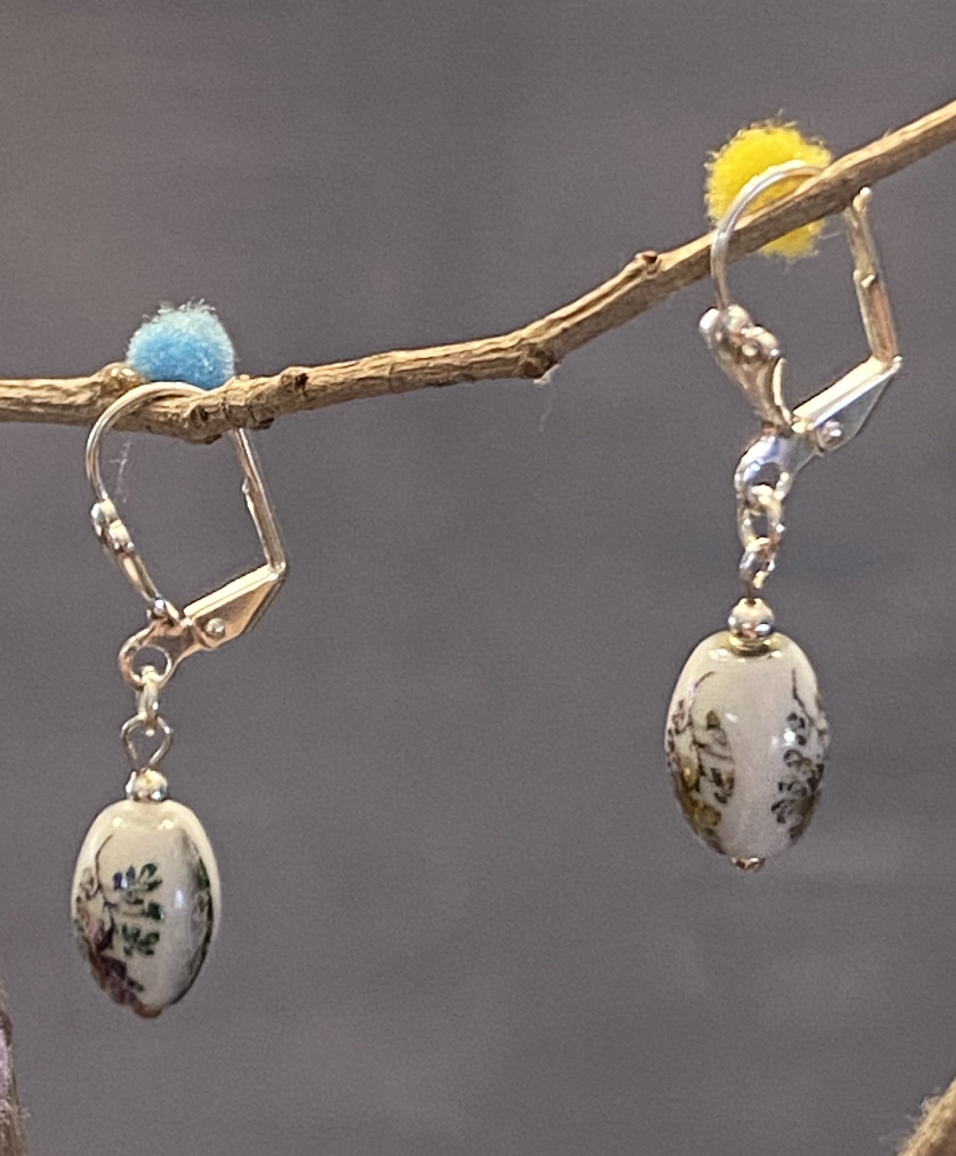 Hazel earrings feature white glass beads with a delicate flower design. Silver-toned base metal, lever backs, approx. 1½" long. Elegant and timeless charm.