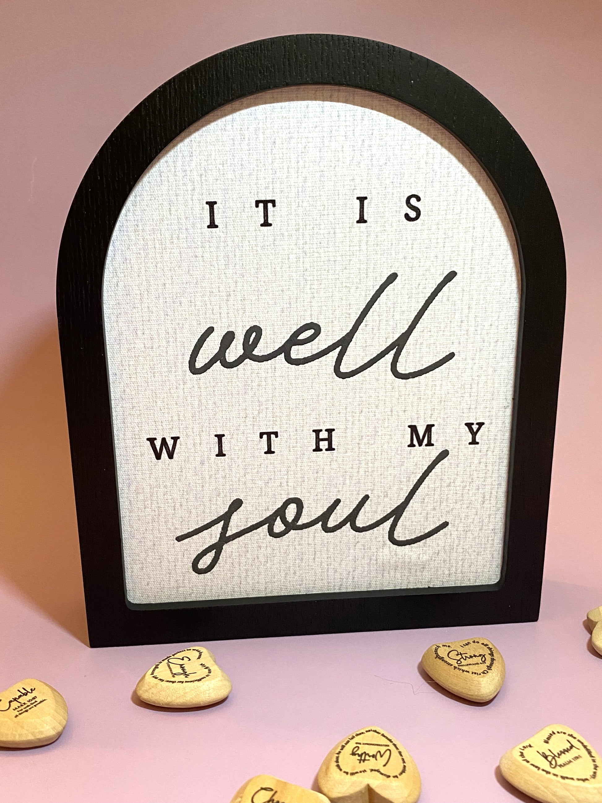 Decorative sign with 'It is well with my soul' text on a pink background with heart-shaped tokens.