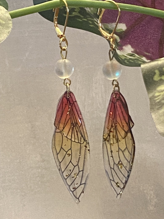 Pink and gold resin butterfly wing earrings with gold-toned lever back hooks, measuring 3½ inches long.