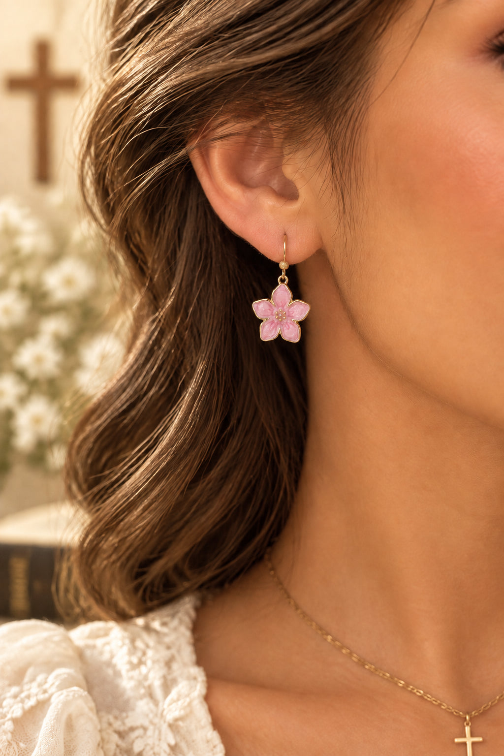 A pair of dangling flower earrings with pink petals and gold-tone metal borders, hooks, and bead details, displayed on a brown kraft card.