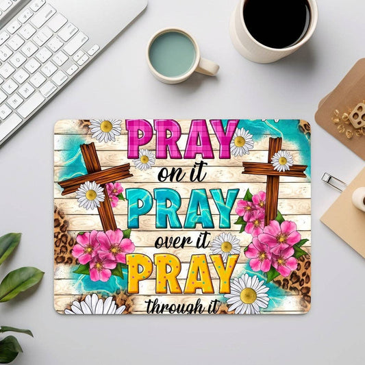 Inspirational mouse pad with teal, aqua, and yellow design, two crosses, flowers, and the phrase “Pray on it, Pray over it, Pray through it.”