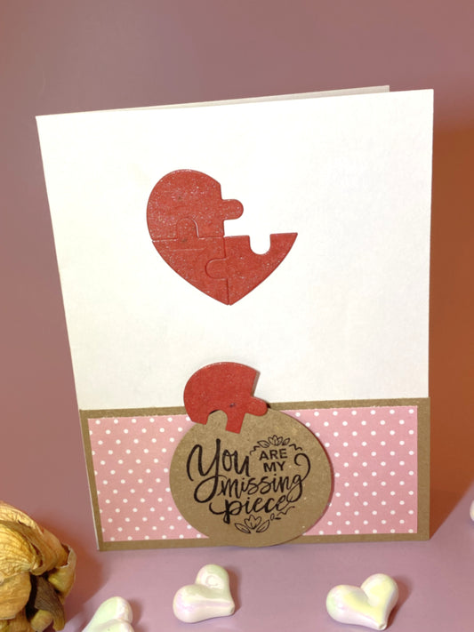 Card with a heart-shaped puzzle piece and 'You are my missing piece' message on a pink background
