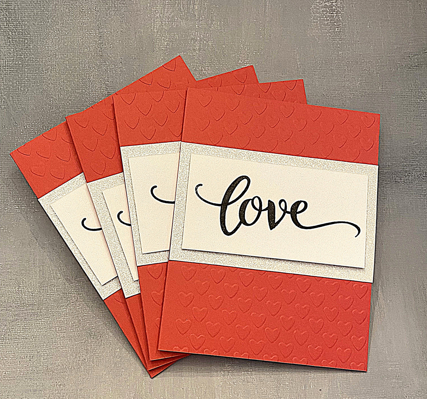 "Set of four handmade red Miss You cards with embossed hearts, glitter accents, and hand-stamped 'Love' on the front, displayed with white envelopes."