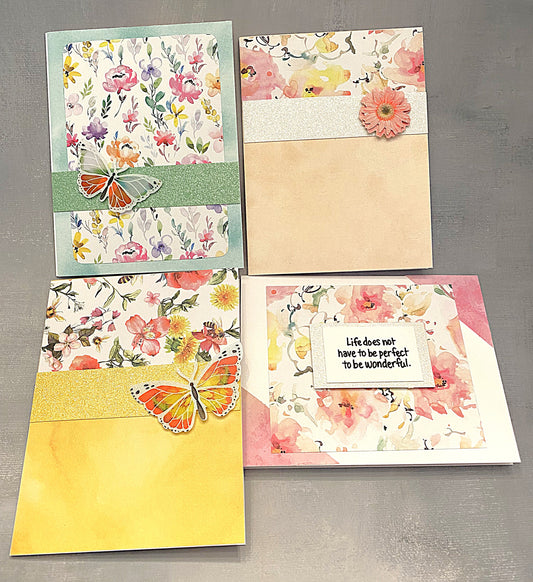 Set of four pastel-colored note cards, each measuring 4¼ by 5½ inches, decorated with floral paper and butterfly embellishments, arranged in a flat lay on a light background."