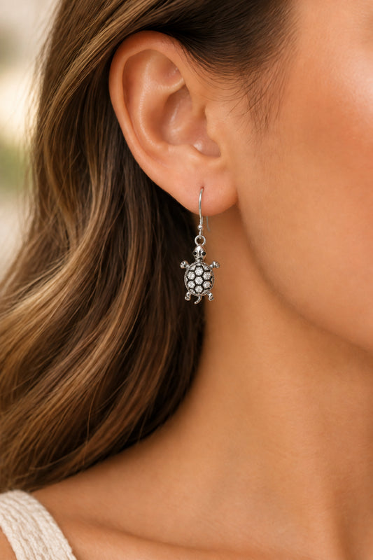 A pair of silver-toned turtle drop earrings embellished with clear rhinestones.