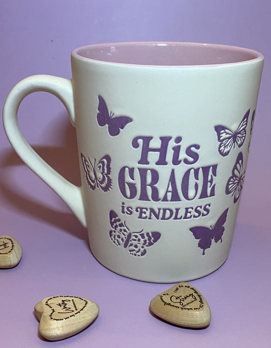 White mug with 'His Grace is Endless' text and butterfly designs on a purple background